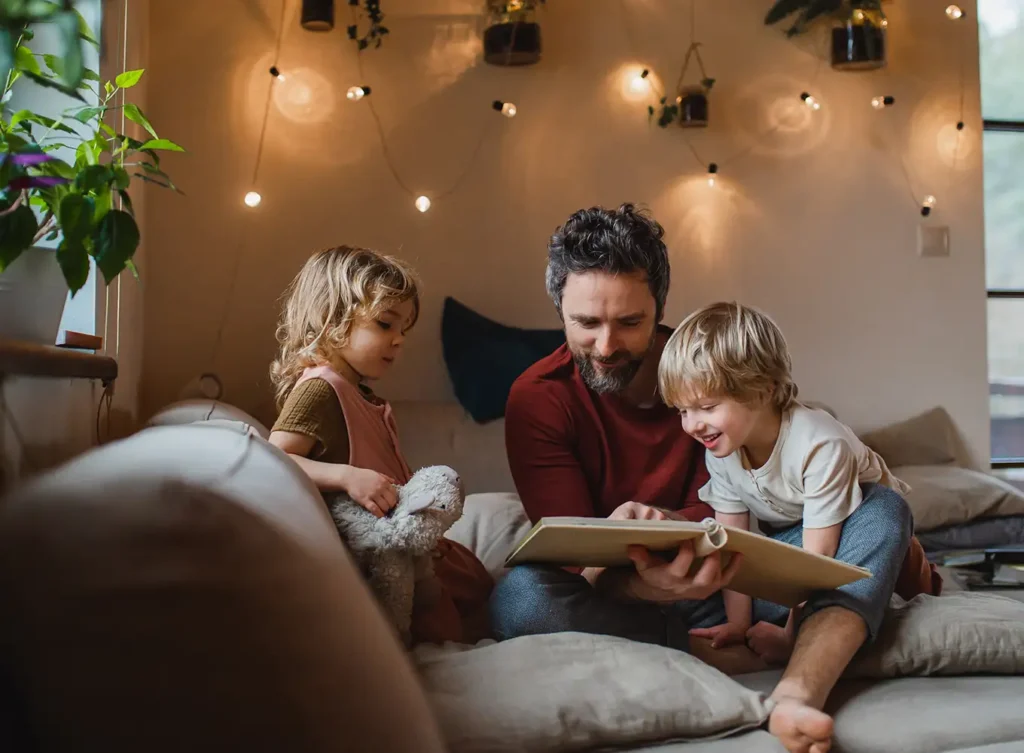 father reading a bed time story to his kids in the comfort of their home