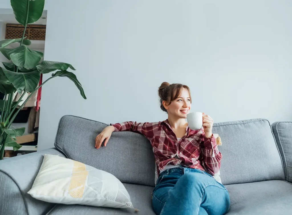 woman sitting comfortably on a couch in her home while breathing in clean air
