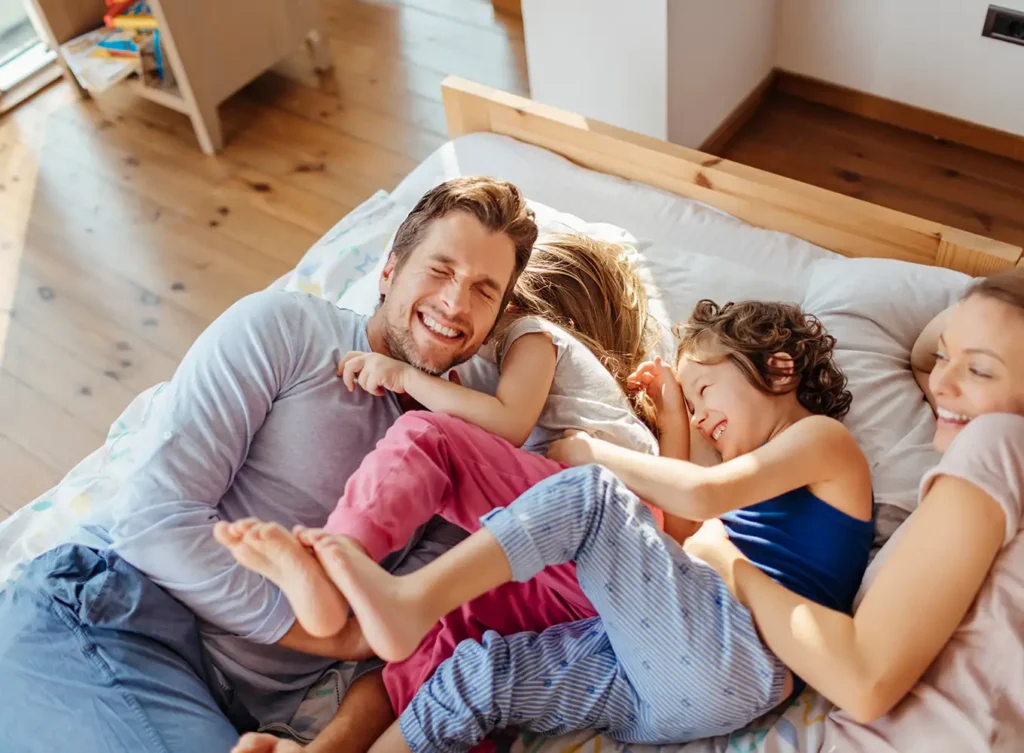 family cuddles on a a bed enjoying their comfortable living space created by their hvac zone control system springfield il