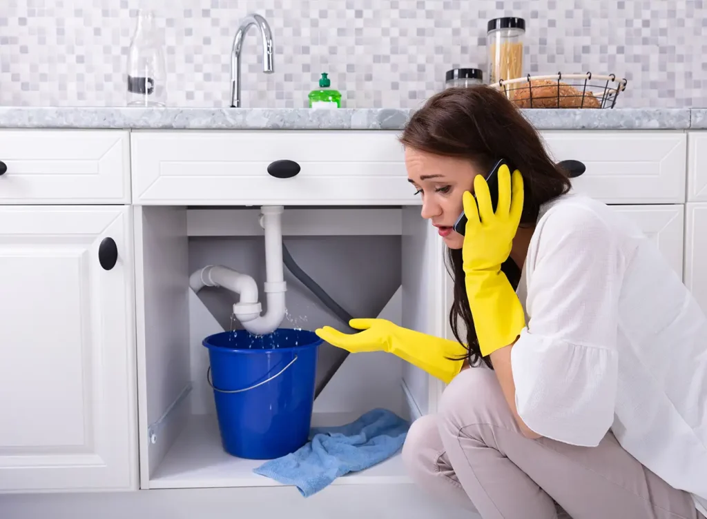 woman with a leak under her sink calling an emergency plumber in springfield illinois