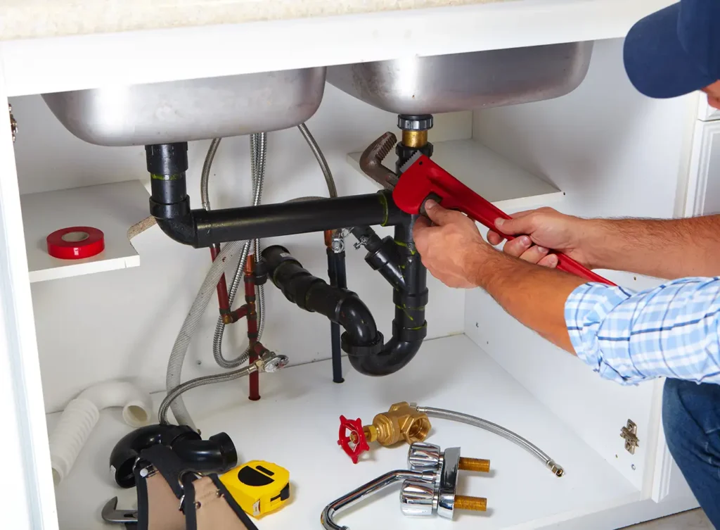 kitchen plumber repairing plumbing system underneath kitchen sink springfield illinois