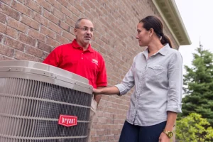 A Bryant technician in Springfield, IL showing a female homeowner her new air conditioner outside the resident's home.