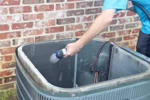 HVAC Technician spraying the inside of a unit with water cleaning off dust and debris outside the home of a Springfield, IL resident.